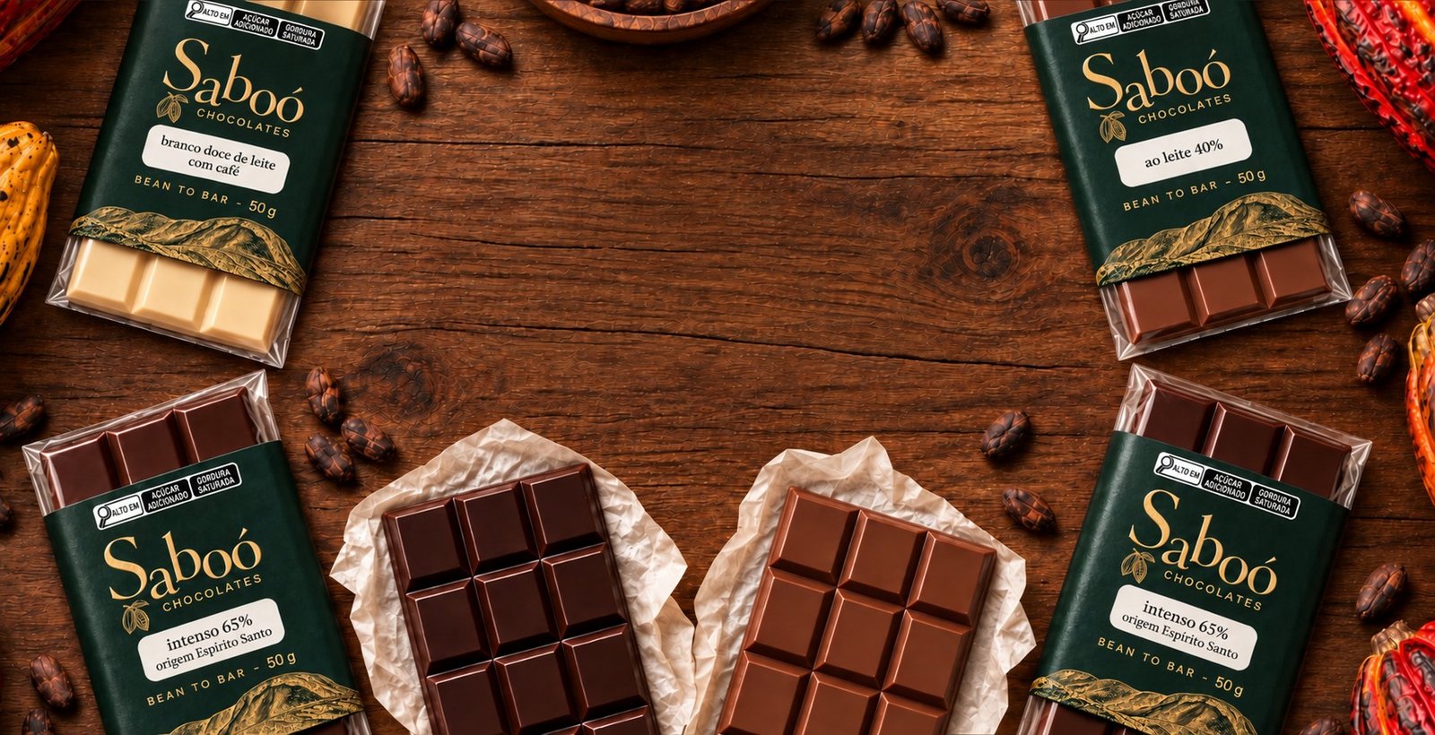 Barras de chocolate Saboó embaladas e abertas, frutos e amêndoas de cacau sobre madeira escura.
